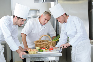 Chef watching apprentice chop vegetables