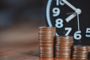 Alarm clock and step of coins stacks on working table, time for savings money concept.