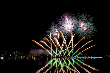 Beautiful fireworks in the night sky on the water surface.