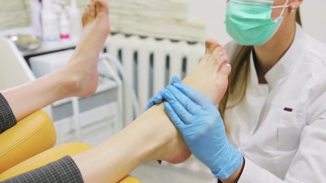 doctor of podiatr makes foot massage to a young girl in clinic