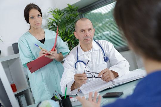 doctor and nurse talking to a patient in medical office