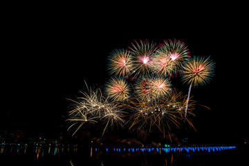 Fototapeta na wymiar Beautiful fireworks in the night sky on the surface of the water in the park.
