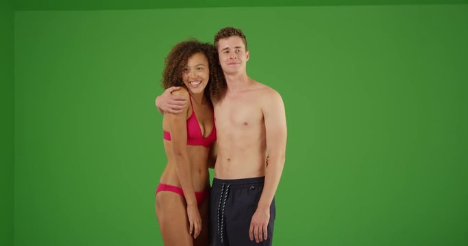 Beautiful young millennial couple enjoying beach together in their swimsuits on green screen. On green screen to be keyed or composited. 
