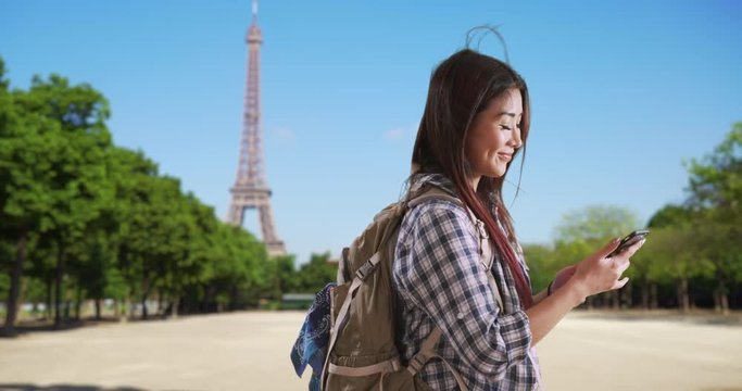 Happy Japanese woman takes cute selfie near Eiffel Tower