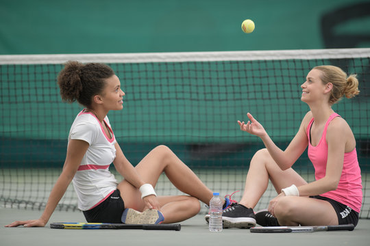 two female tennis player relaxing on the court