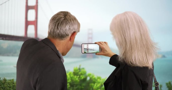 Senior couple taking photos of landmarks with smartphone