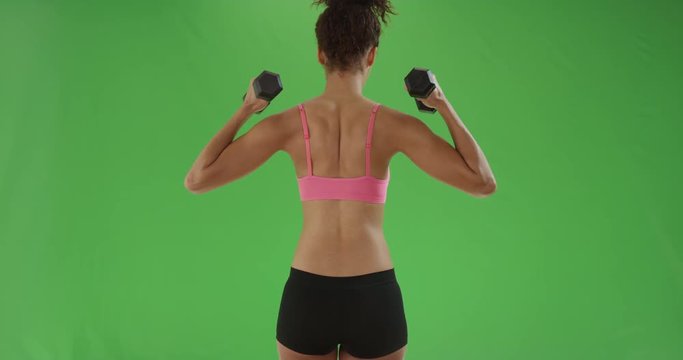 Black millennial girl lifts dumbbells working her biceps for green screen. On green screen to be keyed or composited. 
