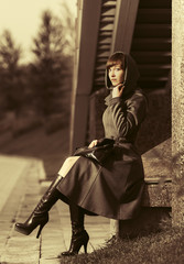 Fototapeta na wymiar Sad young fashion woman in grey classic coat sitting at the wall in night