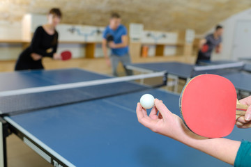 pretty woman playing ping-pong with friends