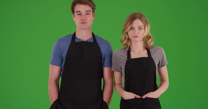 Male and female chefs standing outdoors with hands in apron pockets, staring at camera with serious expression on green screen. On green to be keyed or composited. 