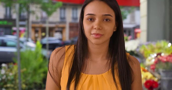 Portrait of beautiful young Latin female outside flower shop in Paris