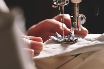 Super slow motion of a professional sewing machine stitching with white thread an Italian haute...