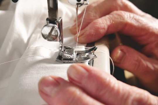 Super Slow Motion Of A Professional Sewing Machine Stitching With White Thread An Italian Haute Couture Fabric, The Seamstress Sews A High Fashion Outfit. Concept Of Industry, Tradition, Fashion