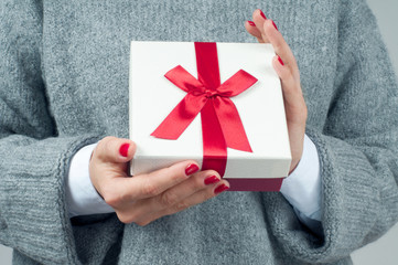 Christmas gift box. Woman in knitted sweater is holding christmas present