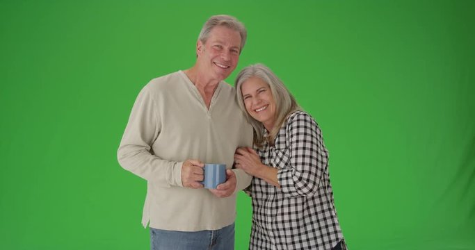 Lovely senior couple smiling at camera on green screen