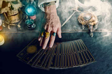 Tarot card / Hand of fortune teller and tarot card on the table under candlelight. Dark tone.