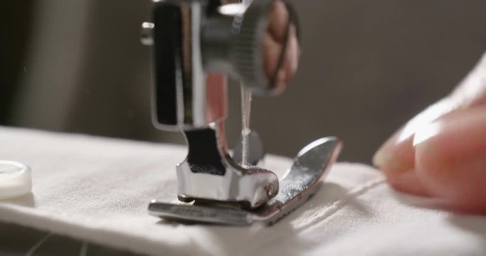 A skilled seamstress sewing with the sewing machine a white fabric, according to the Italian tradition, sews a quality fabric to make a garment fashion clothing. tailoring concept, fashion, tradition