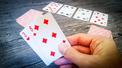 Board gambling game poker male hand holding card three of hearts and six of diamonds, on the table layout playing cards street