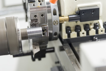 The CNC lathe machine cutting the thread of the pipe.