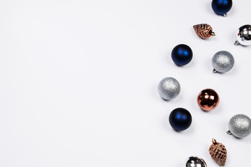 Christmas holiday background. Blue and silver glitter ball and gold pine cone christmas ornaments on a white background with copy-space. Top view.