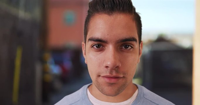 Wide angle close up of handsome Latin male with undercut looking at camera