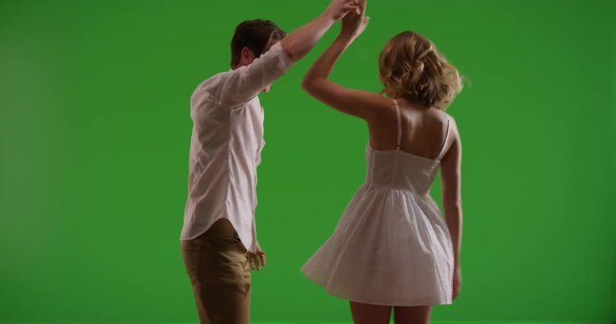 Attractive young couple dancing in contrasty lighting on green screen. On green to be keyed or composited. 
