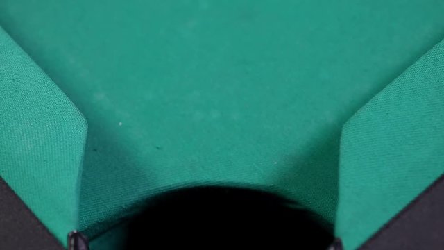 Close up of a billiard ball with number 4 and purple color, falling into the billiard table hole