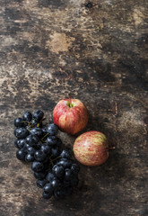 Fresh ripe autumn fruit apples and grapes on rustic wooden background, top view. Free space for text