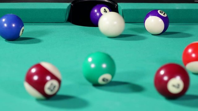 Close up of a white billiard ball hitting the billiard ball number four and get into the hole