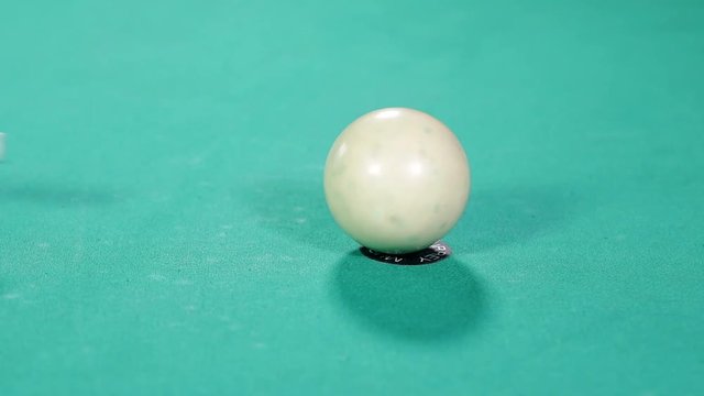 Close up a white billiard ball with a cue stick on the billiard table