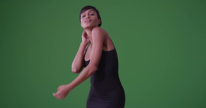Sexy woman in tight black dress dancing on grey background on green screen. On green screen to be keyed or composited. 