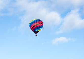 Colorful hot air balloon flying in the blue sky with soft clouds - at Winthrop Balloon Festival, Washington state