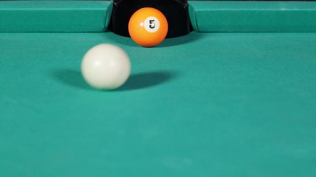 Video footage of a billiard ball number five hit by white ball and get into the billiard table hole