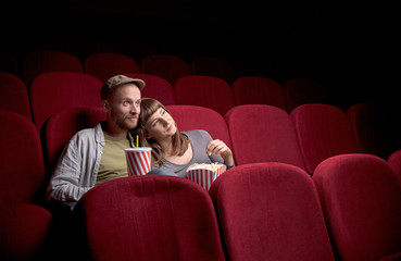 Young couple sitting at red movie theatre