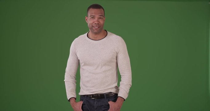 Handsome black man smiling in a trendy white sweater on green screen. On green screen to be keyed or composited. 