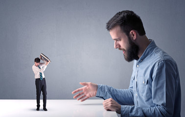 Young businessman fighting with miniature businessman