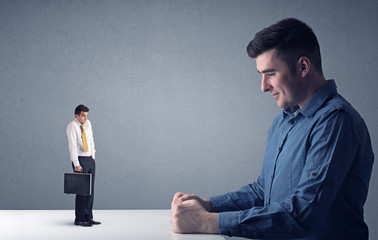 Young businessman fighting with miniature businessman