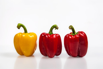 one yellow and two red peppers on white