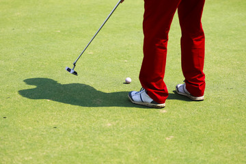 Fototapeta na wymiar Golf player at the putting green hitting ball into a hole