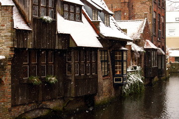 Fototapeta na wymiar Medieval wooden and brick buildings at canal street in Bruges, Belgium. Winter landscape of old historical town in Europe. Winter travel landscape. Christmas and New Year time. Vintage architecture. 