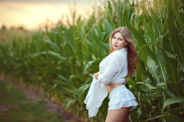 Beautiful woman stands in the field, she turns around and flirts.