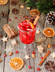 glass of hot mulled wine for the new year with ingredients for cooking, nuts and Christmas decorations