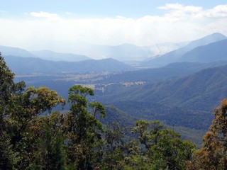 A birds eye view of a valley from the Atherton Tablelands towards Innisfail in Queensland, Australia showing a bush fire in the distance    