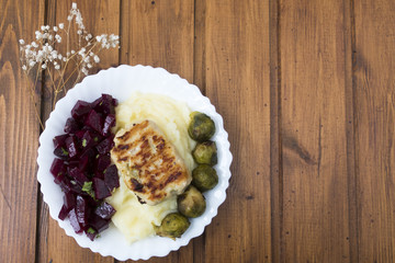 Plate with food consisting of mashed potatoes, beetroot salad, fried Brussels sprouts, meat cutlets. Space for copy space.