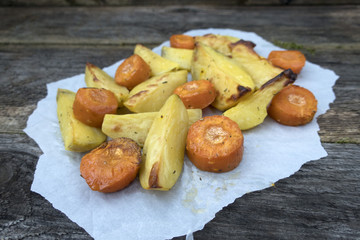 Rustic potatoes and baked carrots on a wooden table.
