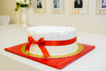 Birthday cake with red bow. Bows on anniversary cakes. Delicious sweet symbolic cooking the festive feast.  