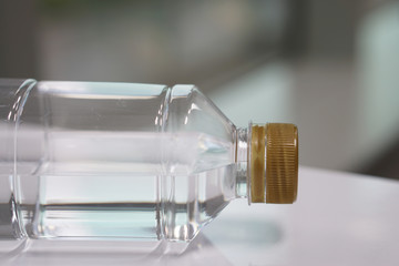  Plastic water bottle lying on the white desk. Closeup beside view