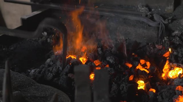 Master blacksmith heats the coals of his forge ready for use