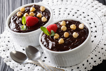 Sweet chocolate pudding decorated with hazelnuts, mint and raspberries close-up. horizontal