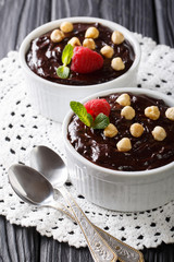 Delicious dessert: chocolate pudding with hazelnuts, mint and raspberries close-up. vertical